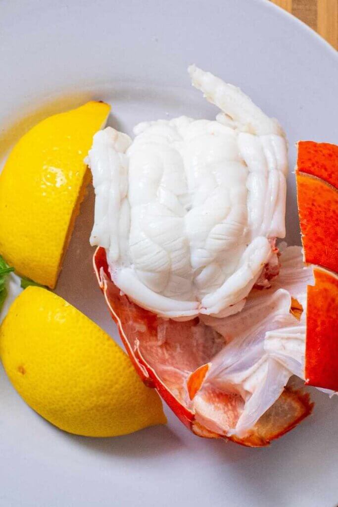 top shot of lobster cooked in the instant pot on white plate with lemons