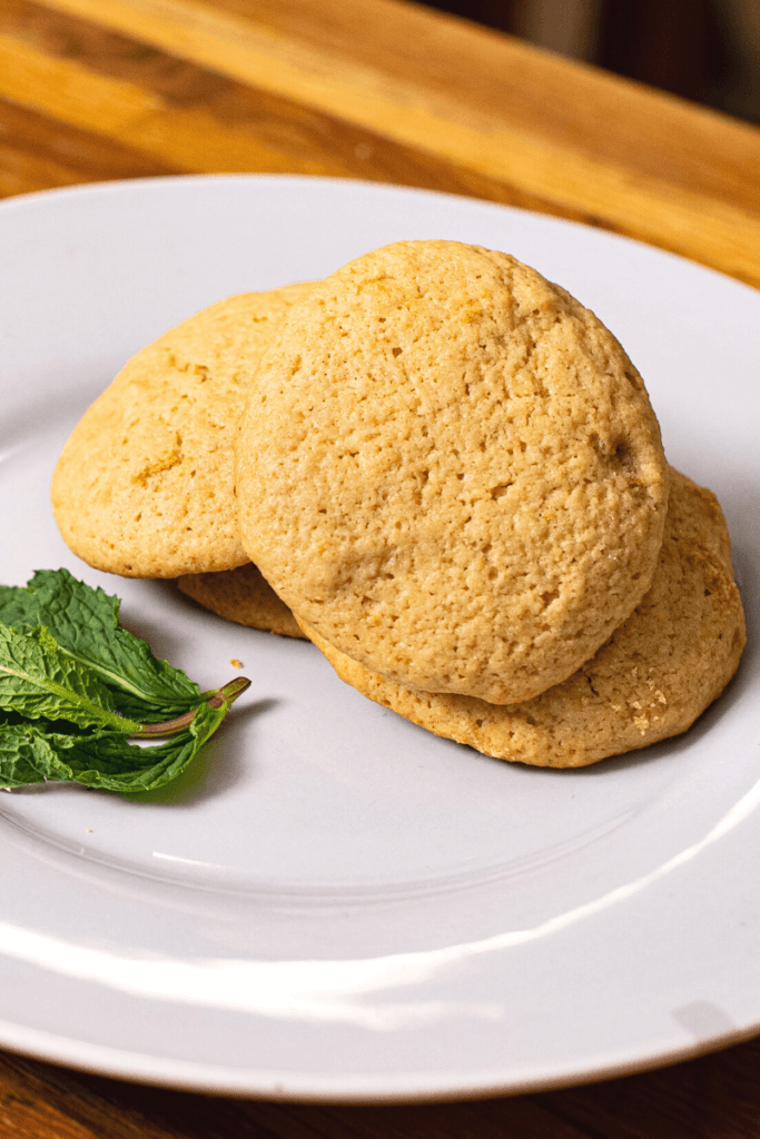 side shot of a stack of olive oil cookies next to garnish