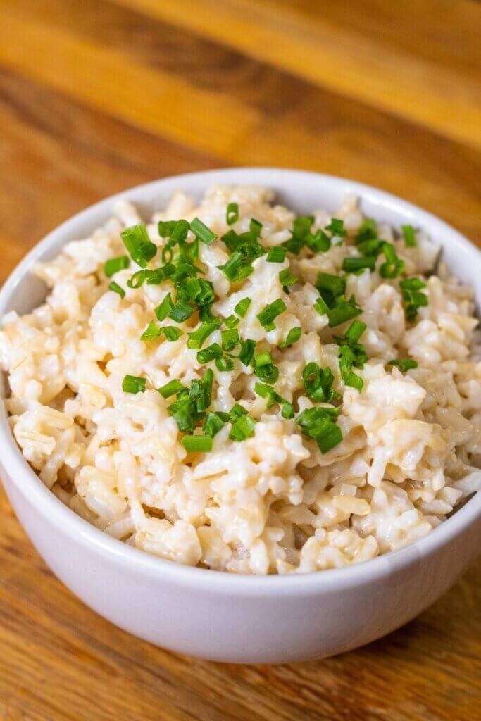coconut lime rice in a white bowl topped with green garnish