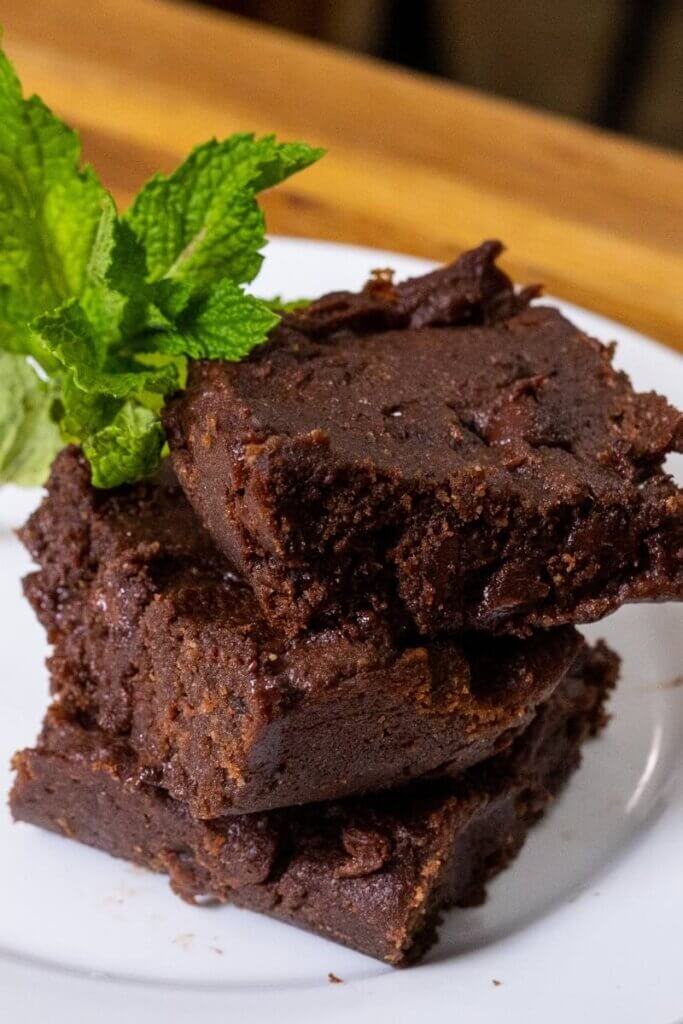 three peanut butter banana brownies stacked on a white plate