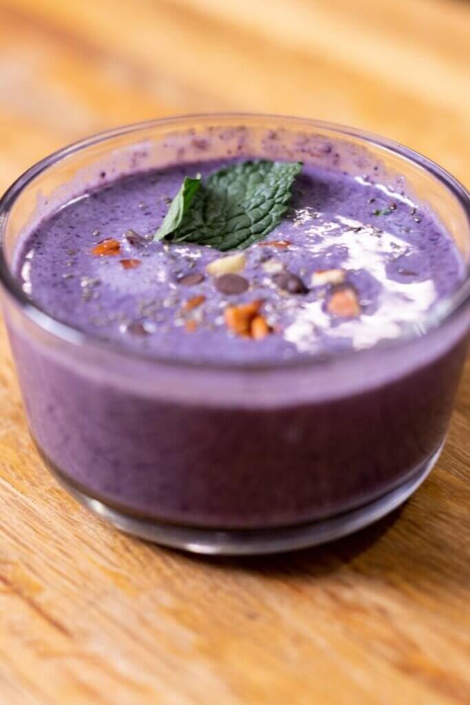 flaxseed pudding with blueberries in a small glass bowl with toppings