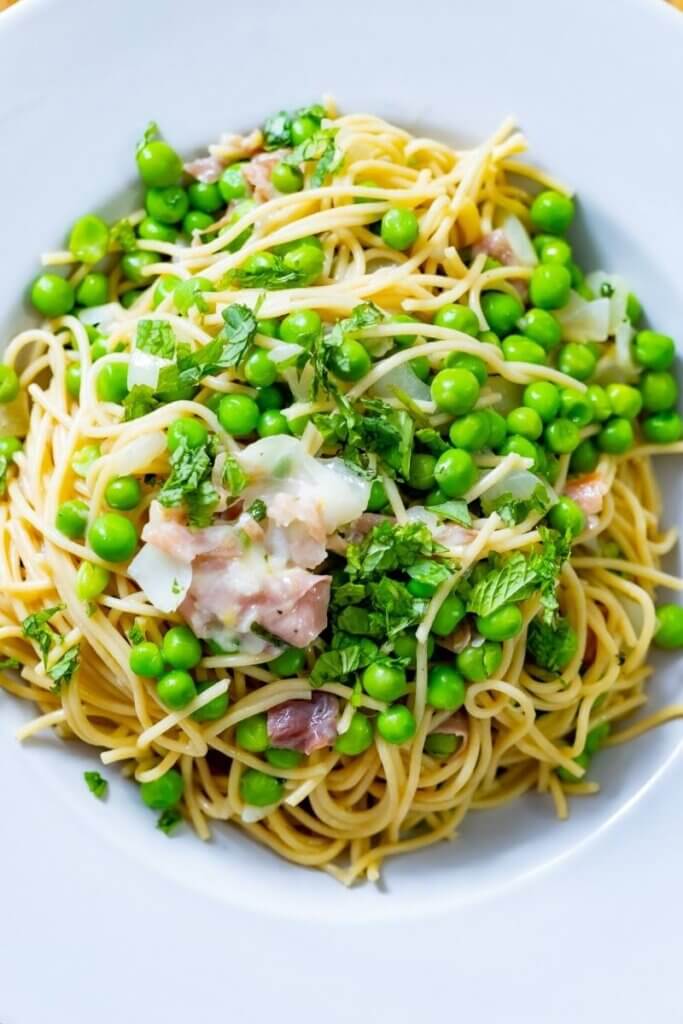 top view of green pea pasta in a large white bowl