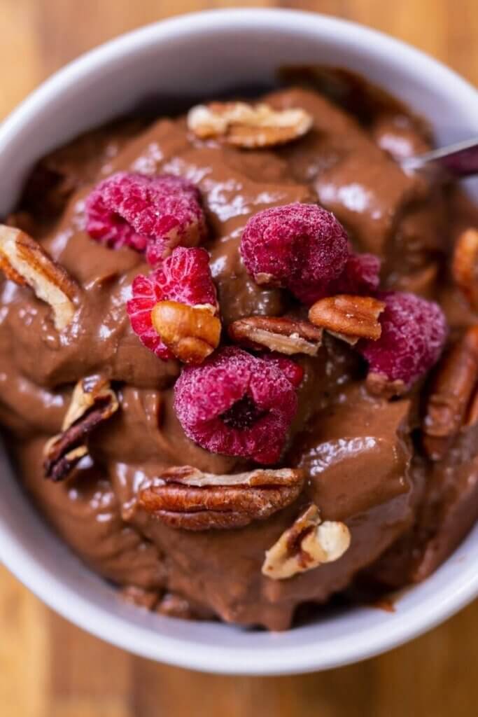 top shot of oat milk chocolate pudding in a white bowl with nuts and berries
