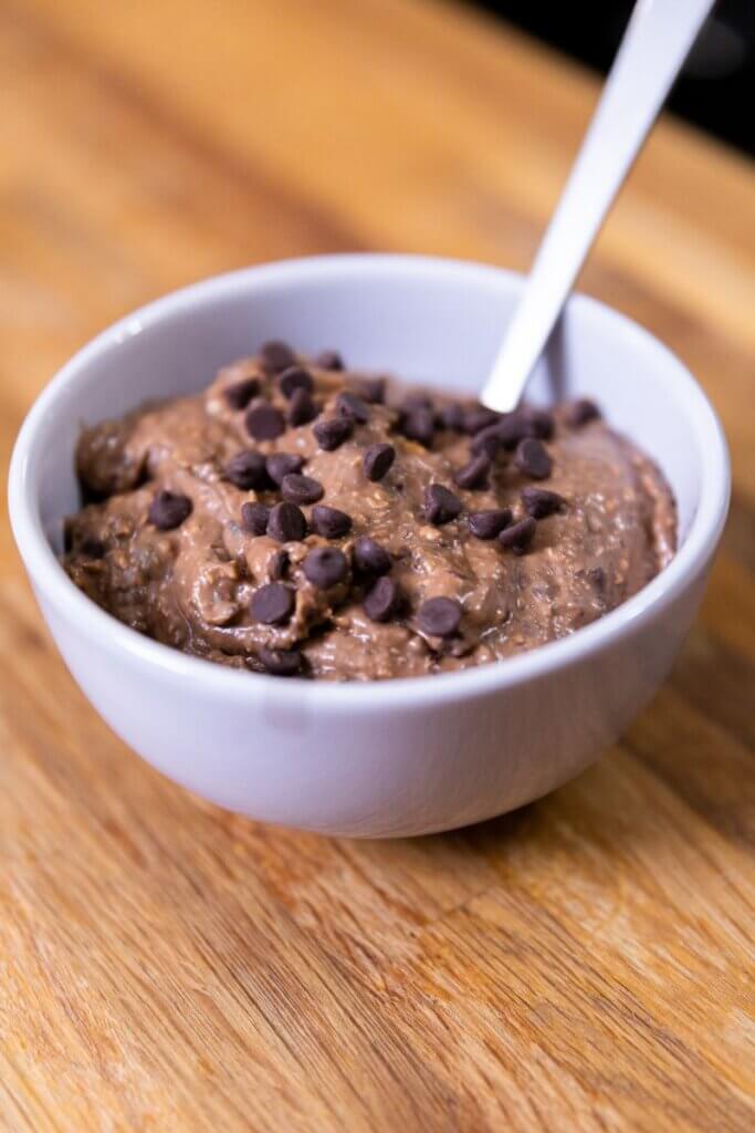 side view of brownie batter in a white bowl with a spoon 