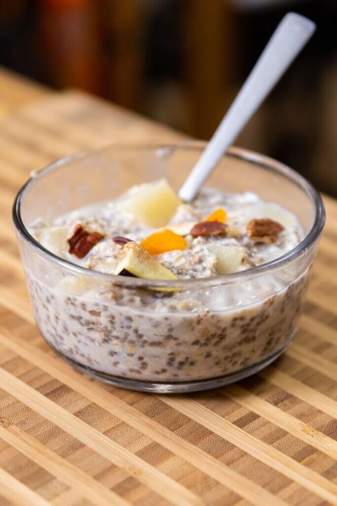 side view of a glass bowl filled with pear overnight oats with a spoon