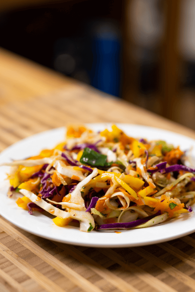 side view of tropical coleslaw on a white plate