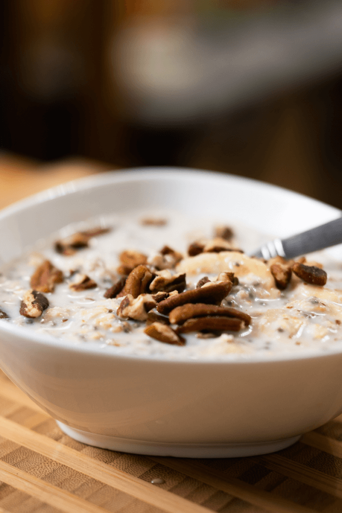 side view of tahini overnight oats in a white bowl with a spoon.