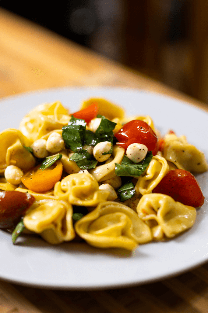 side view of tortellini caprese salad on a large white plate
