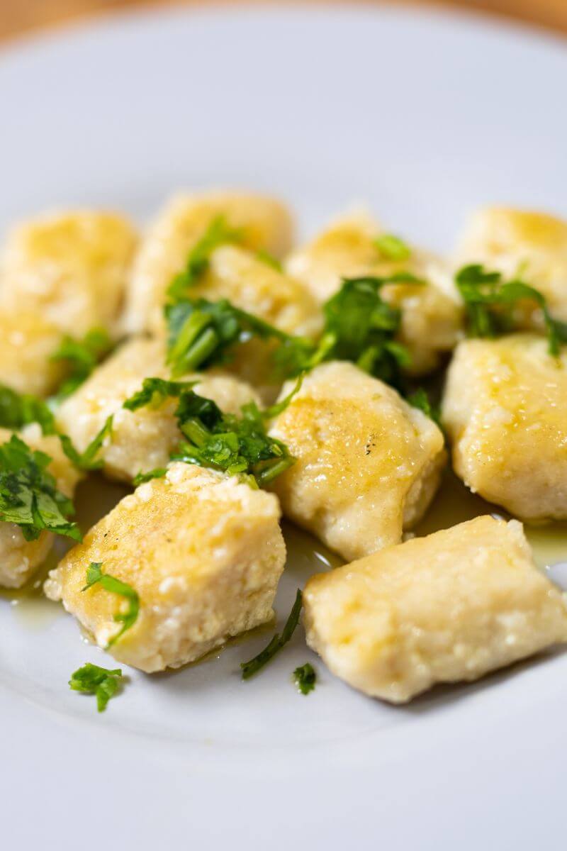 tofu gnocchi on a white plate garnished with parsley.