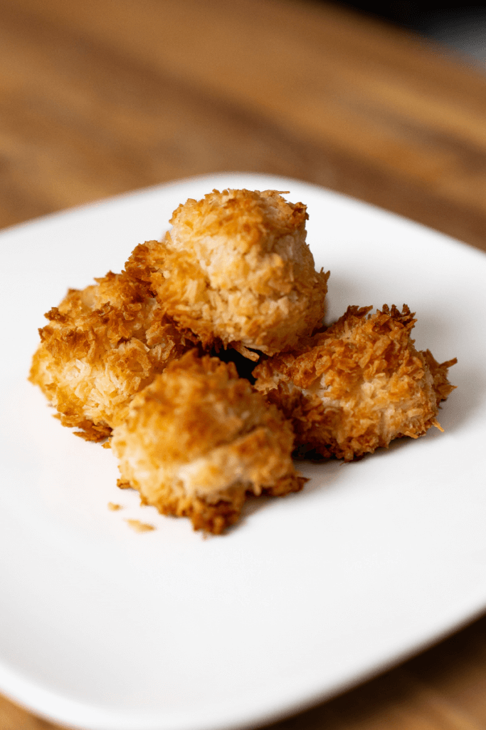 four coconut kiss cookies on a plate.