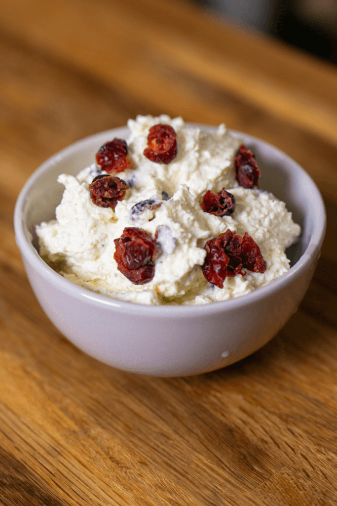 Cranberry whipped feta cheese dip in a white bowl topped with dried cranberries.