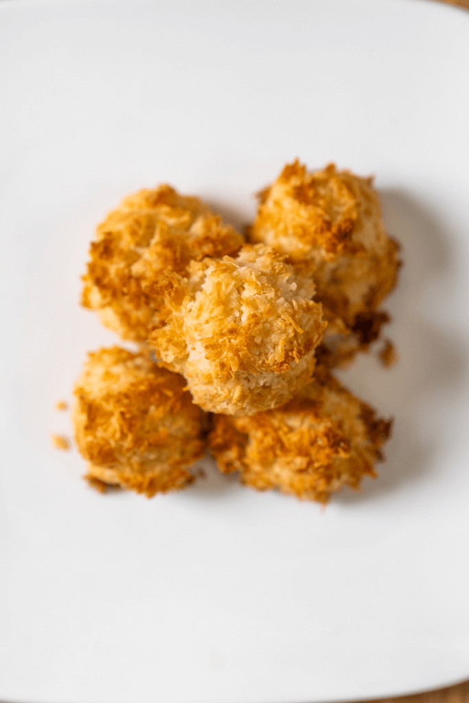 top view of a stack of coconut kisses on a white plate.
