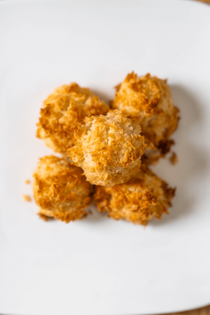 top view of a stack of coconut kisses on a white plate.