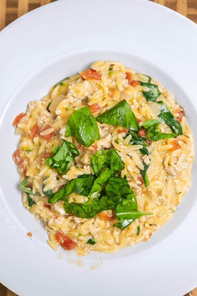 Creamy tomato orzo in a large serving bowl topped with basil.