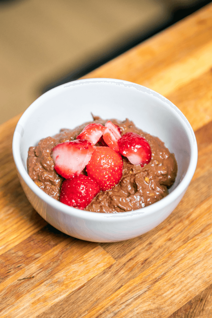 A bowl of homemade vegan avocado chocolate mousse topped with berries.