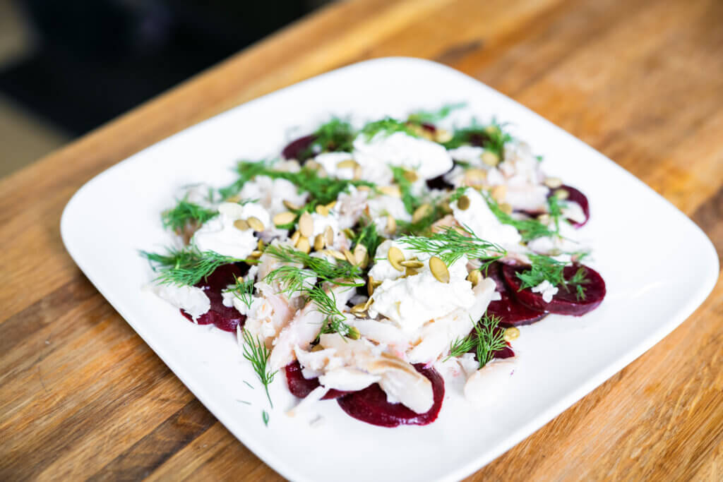 A plate of beets and smoked whitefish garnished with fresh dill.