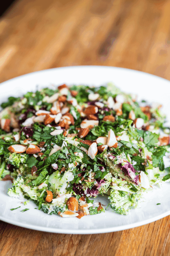 Beef and broccoli salad with nuts on a large white plate.
