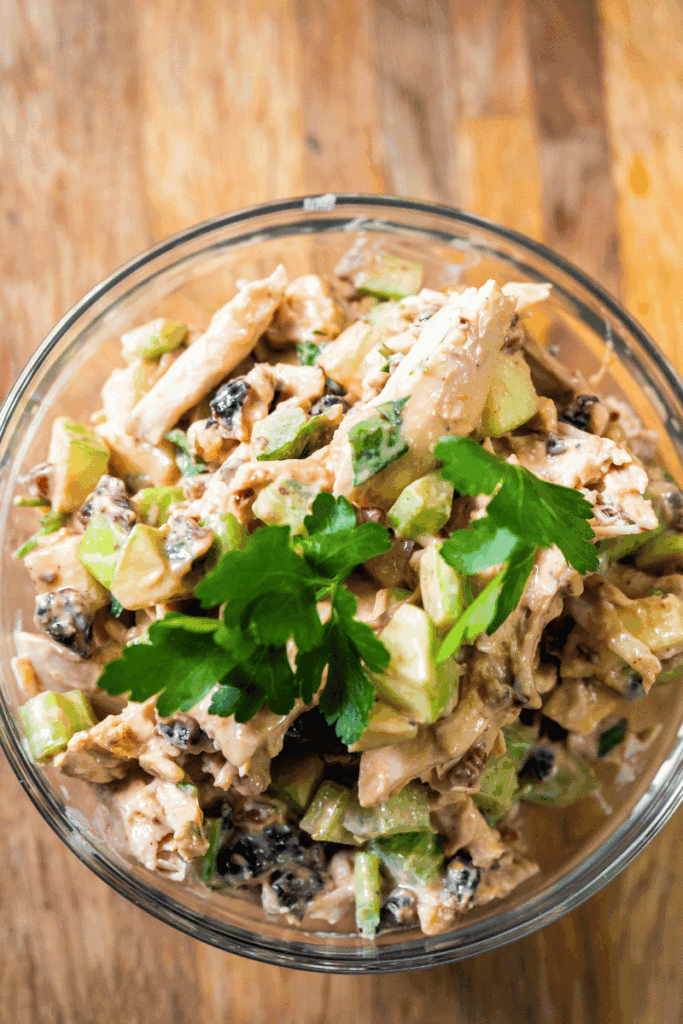 Top view of chicken salad with cherries in a glass mixing bowl. 