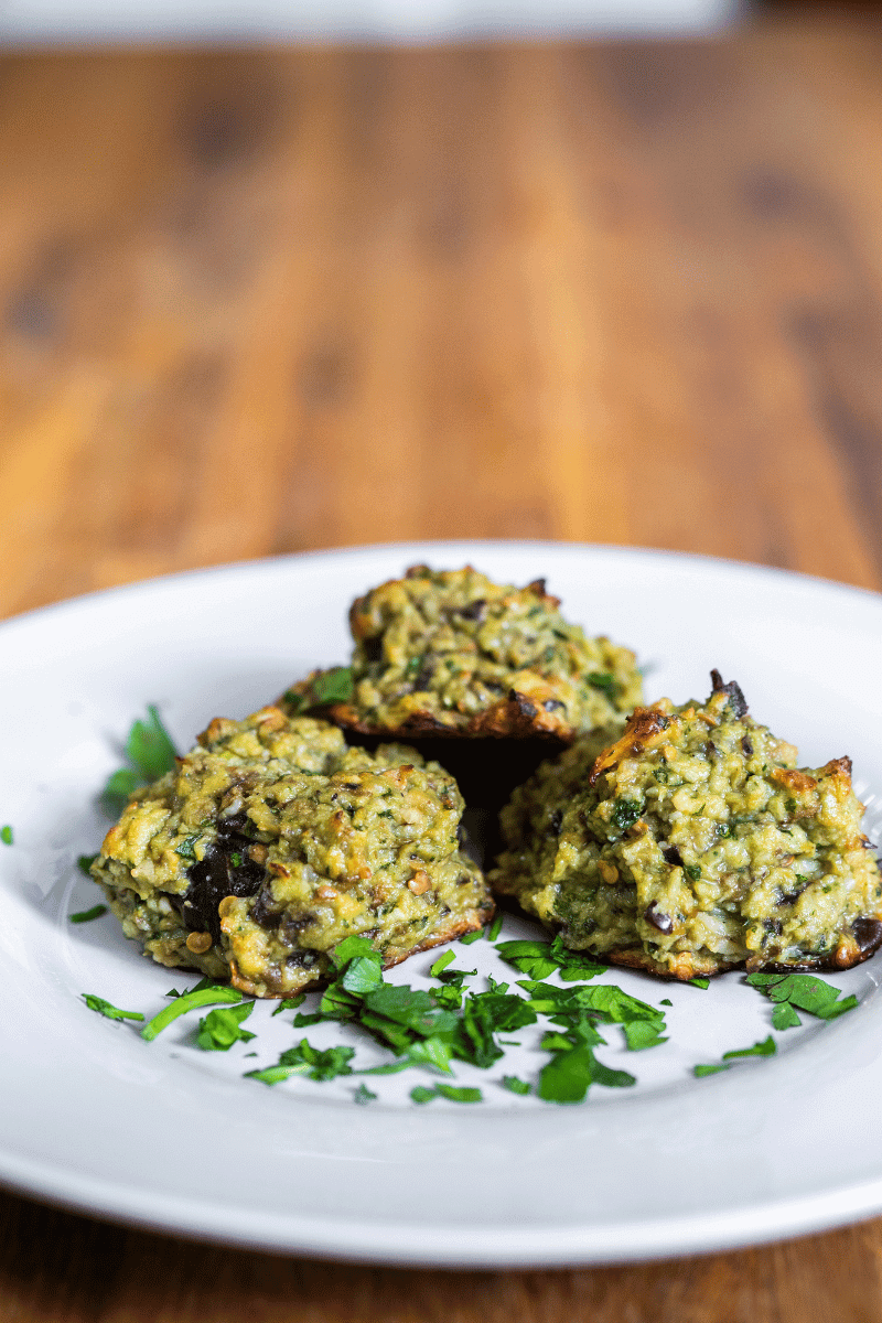 Close up of eggplant parm meatballs on a white plate.
