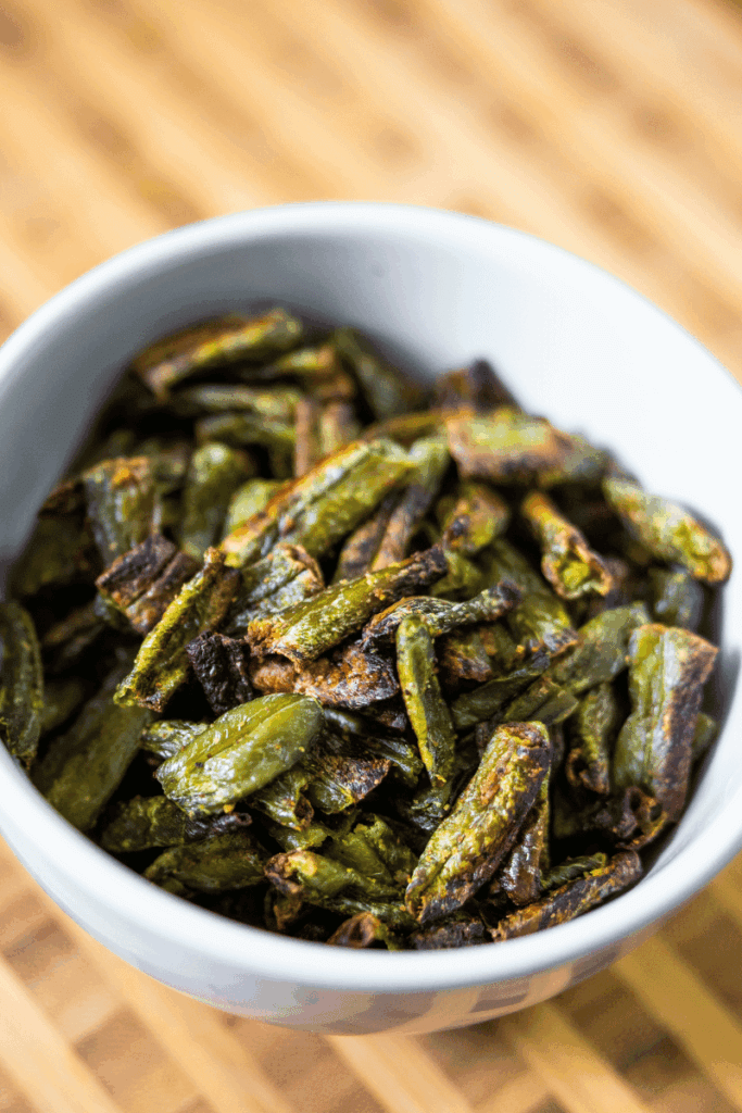 Roasted frozen green beans in a white bowl.