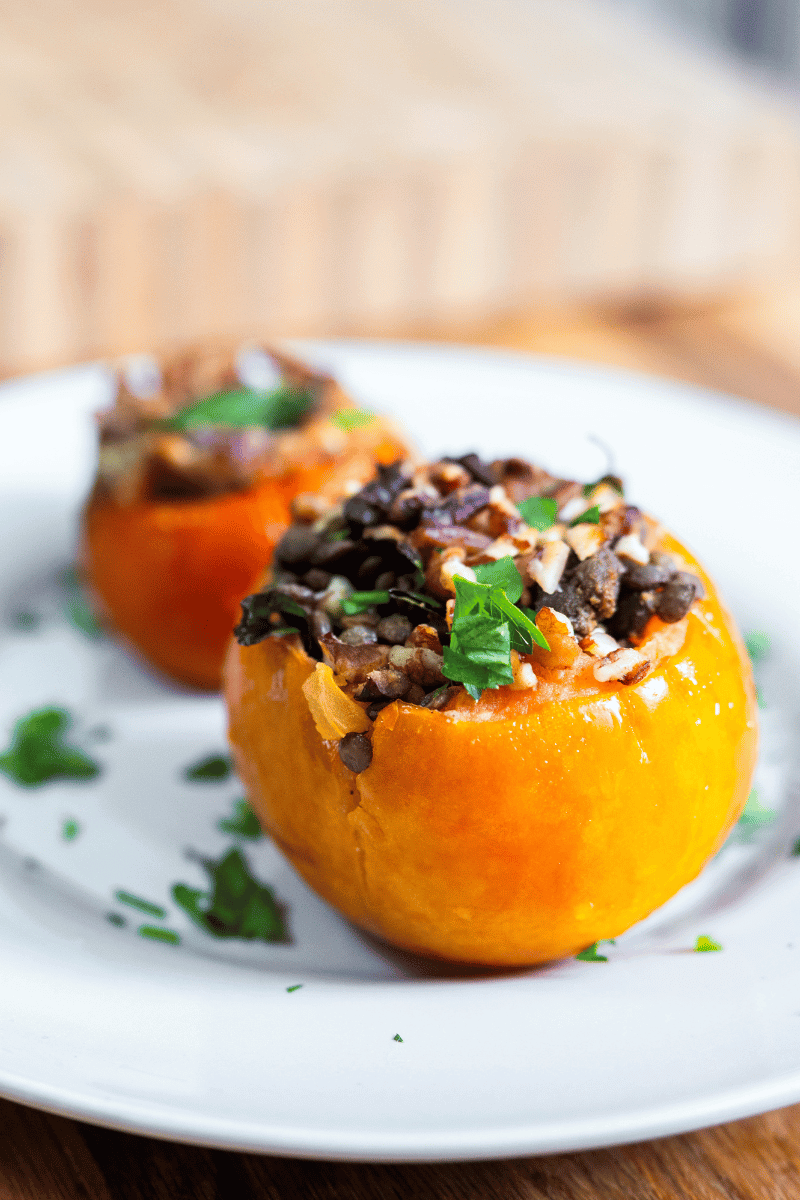 Two large vegan stuffed tomatoes on a white plate.