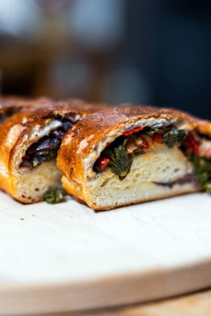 Baked vegetable stromboli resting on a wooden cutting board.