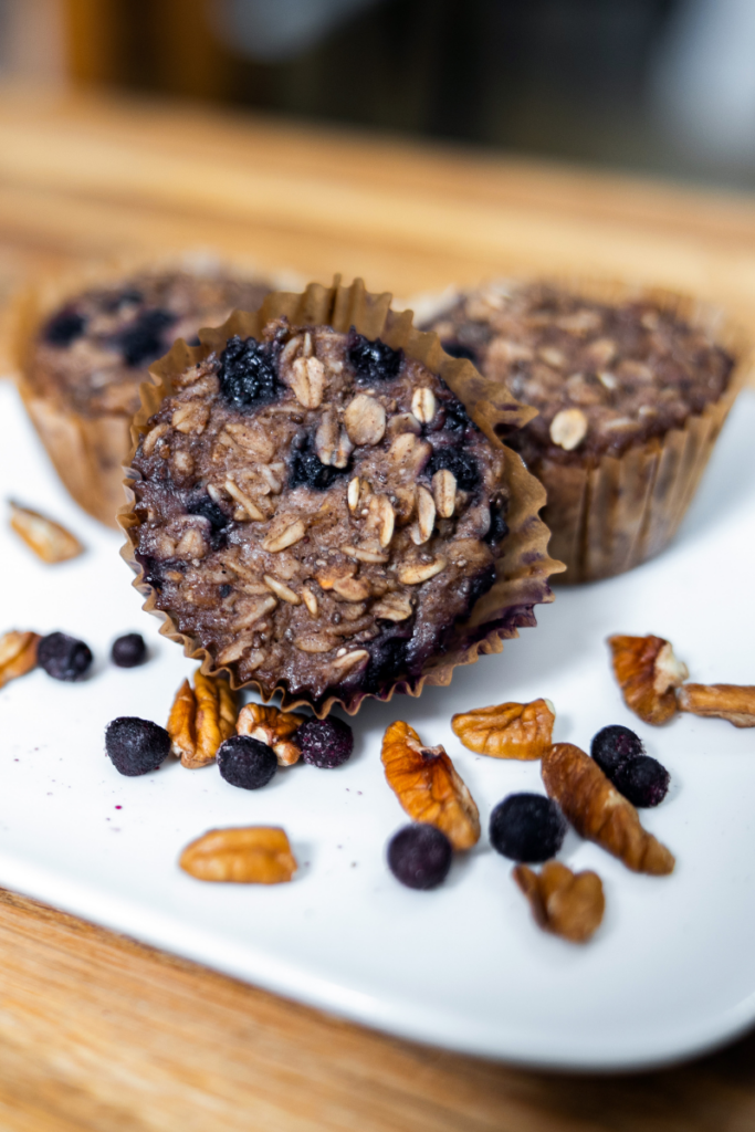 Three vegan oatmeal muffins on a white plate with pecans.