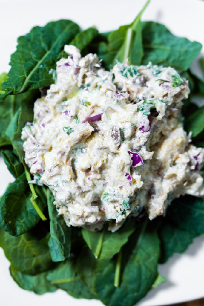 Top view of Smoked mackerel salad on a bed of lettuce on a white plate.
