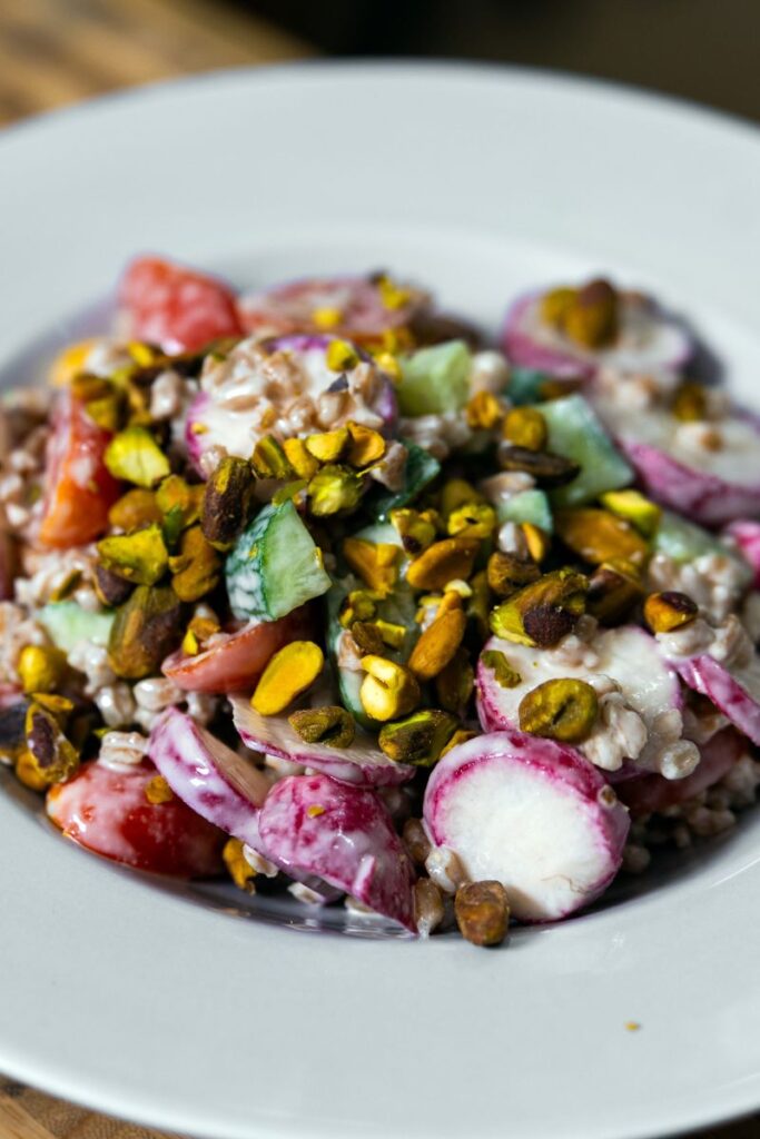 Easy farro salad with homemade lemon tahini dressing in a large white serving bowl.